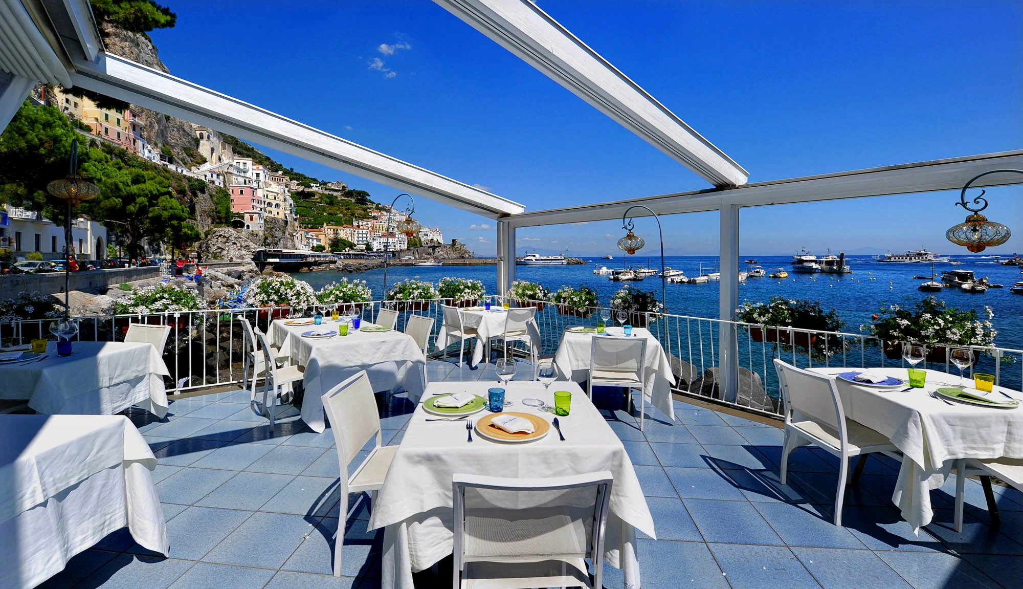 La terrazza del ristorante affacciata sul porticciolo di Amalfi, con i tavoli apparecchiati sotto le tende bianche